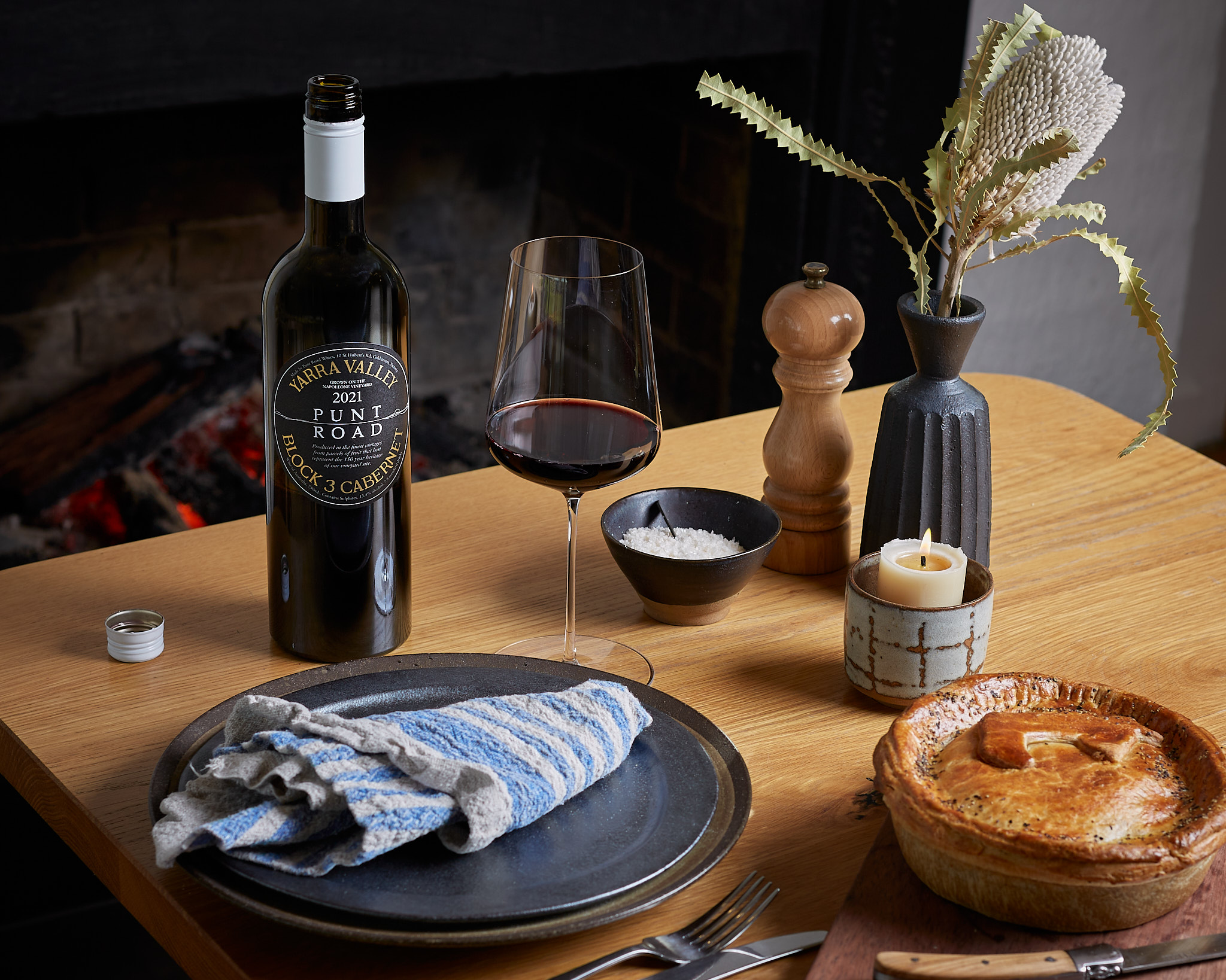 A bottle of Punt Road wine on top of table with wine glass and pot pie. 